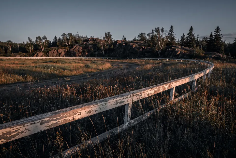 Old racetrack rail curving through tall grass